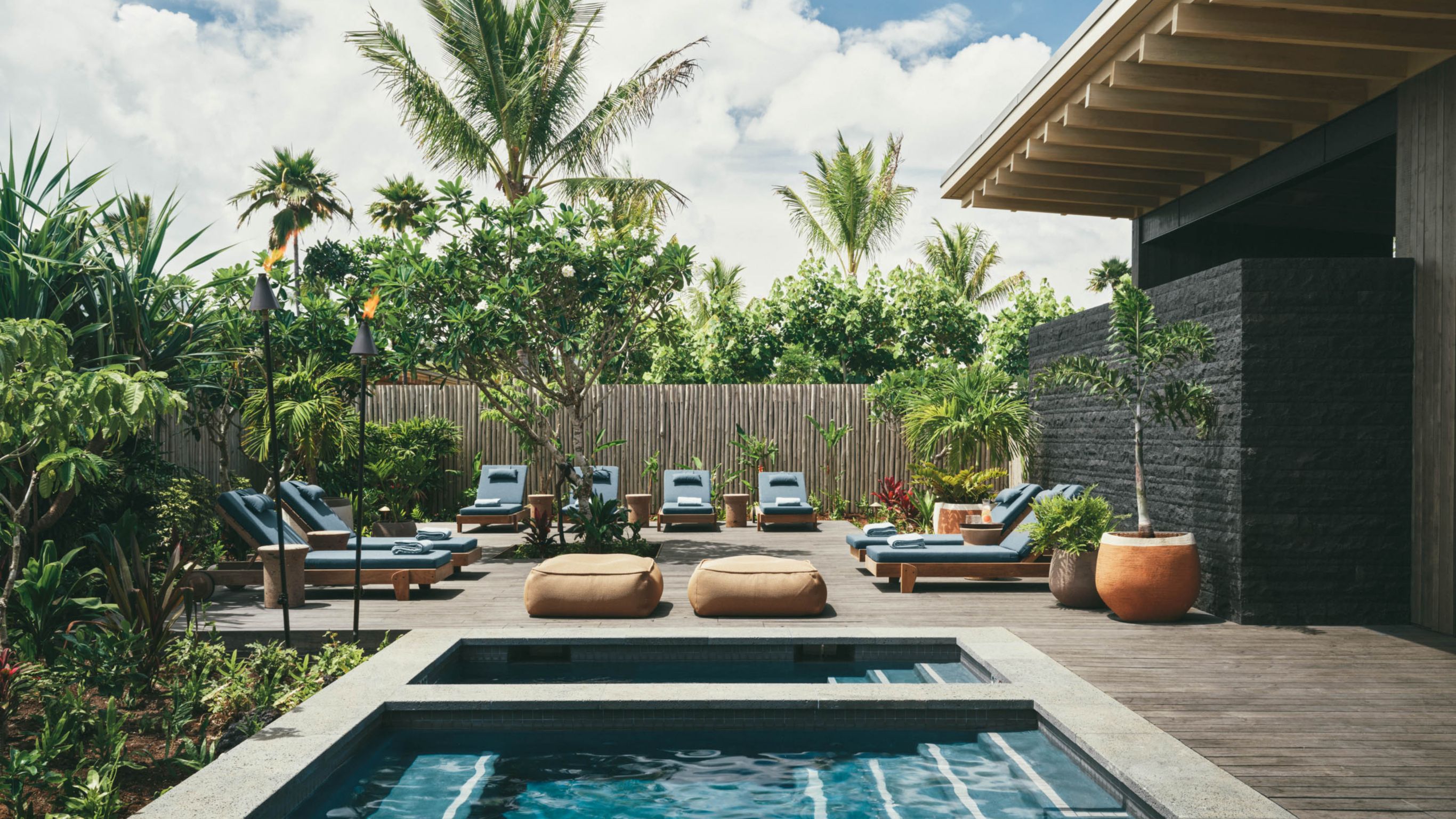 An outdoor Hawaiian spa area with a pool and lounge chairs, surrounded by greenery.
